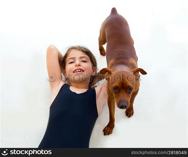 Brunette kid girl with summer swimsuit playing with dog lying on floor