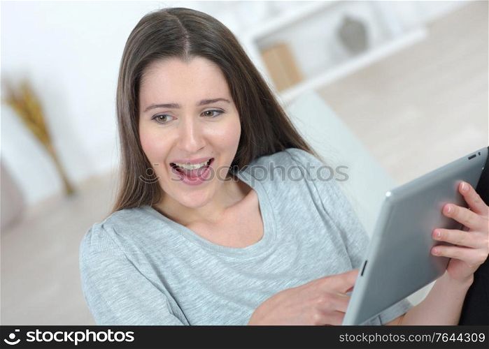 Brunette laughing at something on her tablet