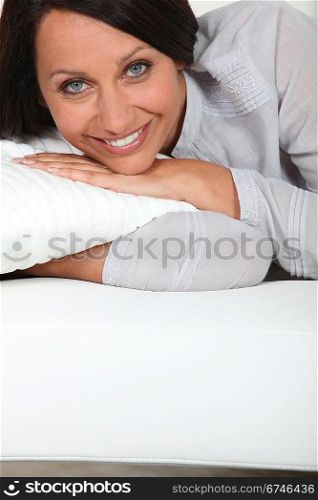 Brunette laying on sofa with pillow