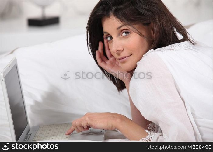 brunette lying in bed with laptop