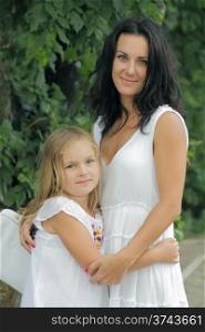 Brunette mother and blond daughter in white