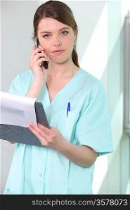 Brunette nurse, holding chart and mobile telephone