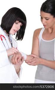 brunette nurse putting bandage on arm of female patient