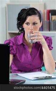 Brunette office worker drinking glass of water