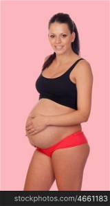 Brunette pregnant woman in underwear on a pink background