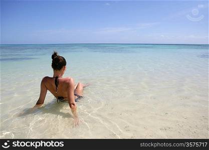 Brunette sat on a beach looking towards the horizon