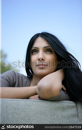 Brunette sat on outdoor sofa