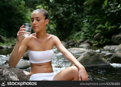 Brunette sat on rock with glass of water