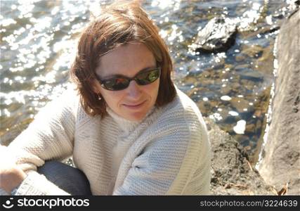 Brunette sitting by edge of lake