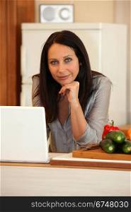 Brunette stood in the kitchen with computer