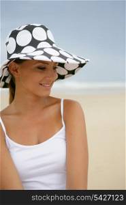 Brunette stood on a beach wearing polka dot hat