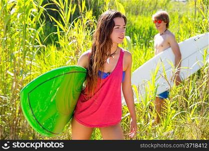 Brunette surfer girl walking in the jungle with surfboard