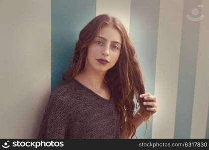 Brunette teen girl portrait in a summer beach blue stripes wall filtered image