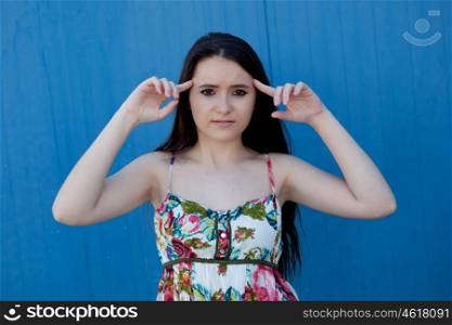 Brunette teenage girl with a blue background wall and headache