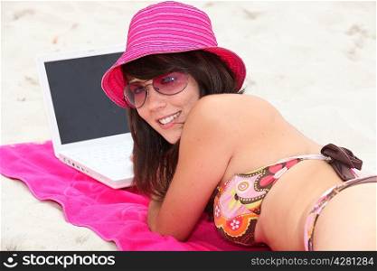 Brunette teenager browsing Internet on beach