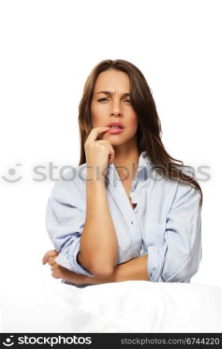 brunette thinking woman sitting in bed. brunette thinking woman sitting in bed on white background