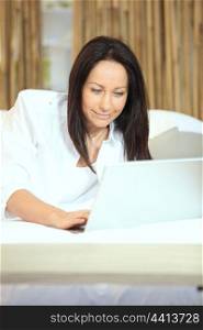 Brunette typing on laptop in bed