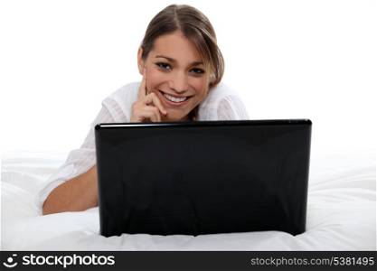 Brunette with laptop laying in bed