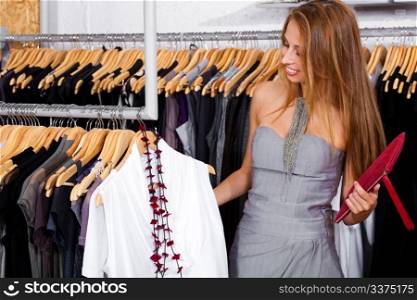Brunette woman considers a top to buy at a retail shop while shopping