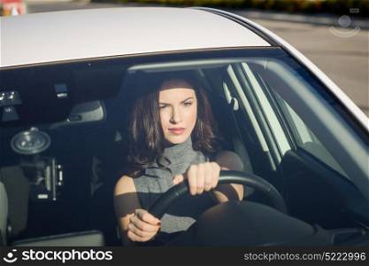 Brunette woman driving a white car in the city