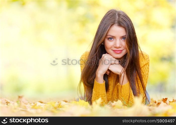 Brunette woman laying in autumn park. Portrait of a beautiful young brunette woman laying in the autumn park