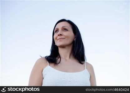 Brunette woman looking at side with a blue sky of background