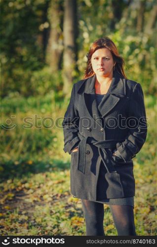 Brunette Woman outdoors wearing warm black coat autumn park. Woman standing outdoors