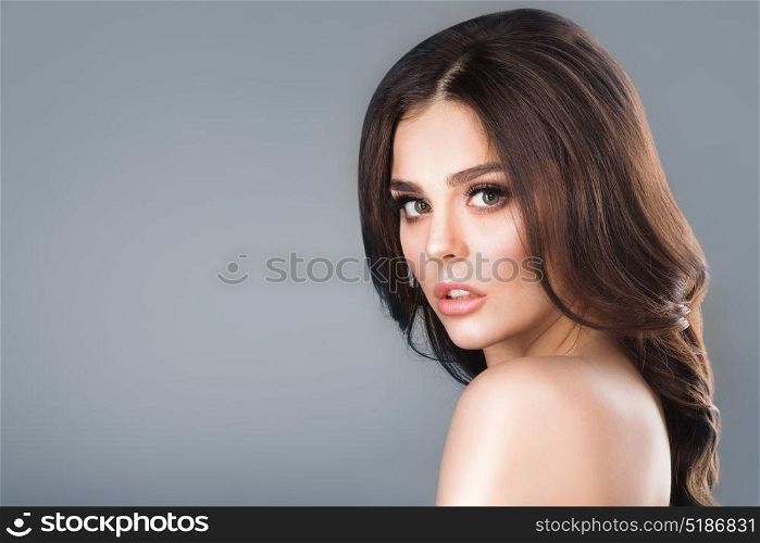 Brunette woman portrait. Beauty studio portrait of brunette woman with natural make-up over gray background