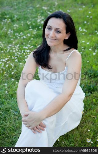 Brunette woman sitting on a flowered meadow