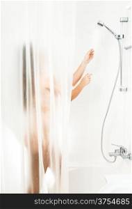 Brunette woman washing in shower behind transparent curtain