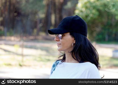 Brunette woman with black hat in the park, enjoying the nature