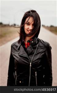 Brunette woman with black leather jacket in a lonely road
