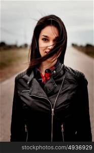 Brunette woman with black leather jacket in a lonely road