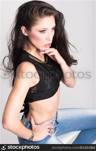 Brunette woman with blue eyes wearing sweater and blue jeans on white background. Studio shoot