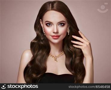 Brunette woman with curly hair. Brunette Girl with Long Healthy and Shiny Curly Hair. Care and Beauty. Beautiful Model Woman with Wavy Hairstyle. Make-Up and Jewelry