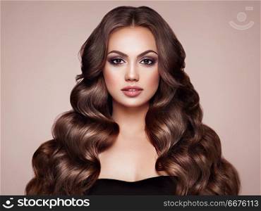 Brunette woman with curly hair. Brunette Girl with Long Healthy and Shiny Curly Hair. Care and Beauty. Beautiful Model Woman with Wavy Hairstyle. Make-Up and Black Dress