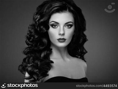 Brunette woman with curly hairstyle. Beautiful girl with long wavy hair. Perfect makeup. Fashion photo. Black and White
