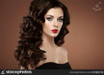 Brunette woman with curly hairstyle. Beautiful girl with long wavy hair. Perfect makeup. Fashion photo