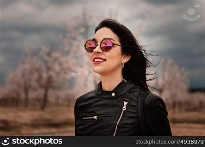 Brunette woman with leather jacket surrounded of flowery almond trees
