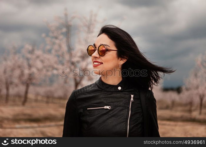 Brunette woman with leather jacket surrounded of flowery trees