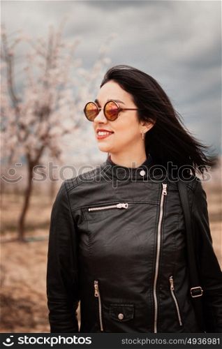 Brunette woman with leather jacket surrounded of flowery trees