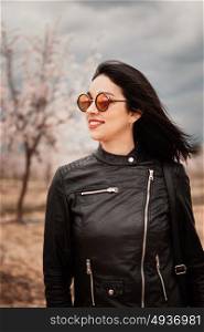 Brunette woman with leather jacket surrounded of flowery trees