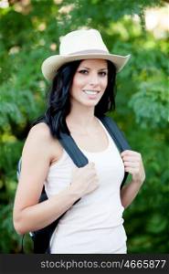 Brunette woman with straw hat walking through the woods