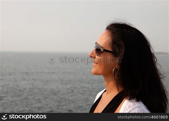 Brunette woman with sunglasses on shore looking at the horizon