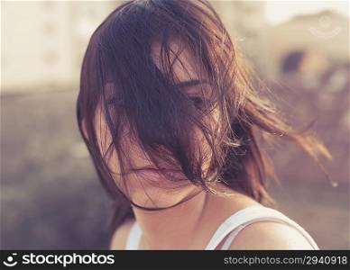 brunette women on the roof of the building, hair over face, vintage toned image, summertime freedom concept