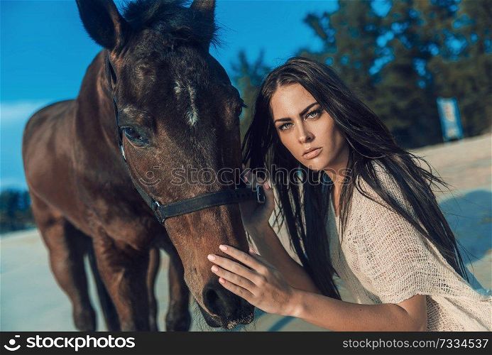 Brunette young woman posing with a majestic stallion
