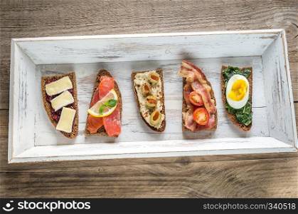 Bruschetta with different toppings on the wooden tray