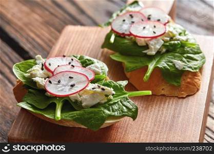 Bruschetta with feta cheese, radish and cucumber on wooden background, copy space. Healthy vegetarian snack. Bruschetta with radishes, spinach and curd cheese with flax seeds on a wooden background.