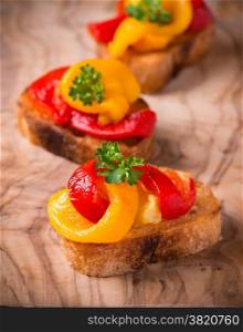 Bruschetta with grilled bell pepper over olive wood board, selective focus