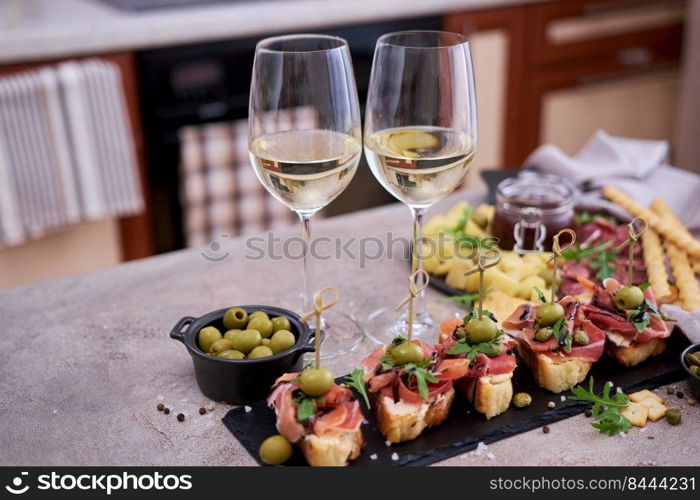 bruschetta with prosciutto ham and capers with traditional antipasto meat plate on background.. bruschetta with prosciutto ham and capers with traditional antipasto meat plate on background